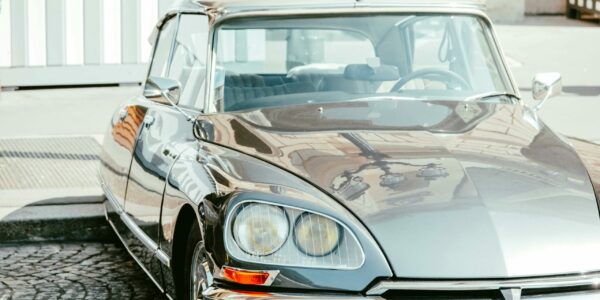 pexels-photo-9328725-9328725 A vintage grey Citroen sedan parked on stone pavement with reflective shine.